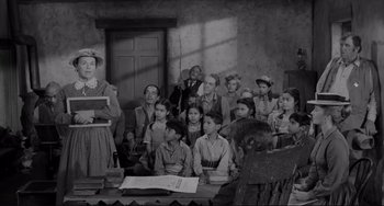 Movie still from “The Man Who Shot Liberty Valance” (1962), directed by John Ford – A group of people sitting in front of a wooden table; Wide shot, High angle
