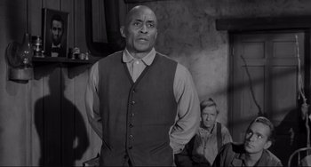 Movie still from “The Man Who Shot Liberty Valance” (1962), directed by John Ford – A man standing in front of another man; Medium shot, Over the shoulder angle