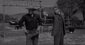 Movie still from “The Man Who Shot Liberty Valance” (1962), directed by John Ford – A man pointing a gun at another man in a cowboy hat; Medium shot, Low angle