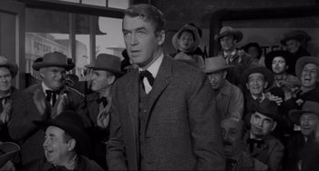 Movie still from “The Man Who Shot Liberty Valance” (1962), directed by John Ford – A black and white photo of a man in a suit and tie; Medium shot, Over the shoulder angle