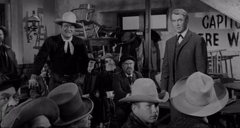 Movie still from “The Man Who Shot Liberty Valance” (1962), directed by John Ford – A black and white photo of a group of men wearing hats; Medium shot, Over the shoulder angle