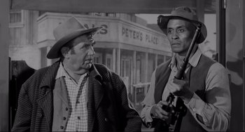 Movie still from “The Man Who Shot Liberty Valance” (1962), directed by John Ford – A black and white photo of two men in cowboy hats; Medium shot, Over the shoulder angle