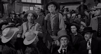 Movie still from “The Man Who Shot Liberty Valance” (1962), directed by John Ford – A black and white photo of a group of men wearing hats; Medium shot, Over the shoulder angle