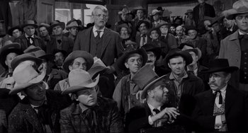 Movie still from “The Man Who Shot Liberty Valance” (1962), directed by John Ford – A black and white photo of a group of men wearing hats; Medium shot, Over the shoulder angle