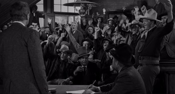 Movie still from “The Man Who Shot Liberty Valance” (1962), directed by John Ford – A group of people sitting around a table with papers; Wide shot, High angle