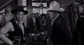Movie still from “The Man Who Shot Liberty Valance” (1962), directed by John Ford – A group of men standing next to each other in a room; Medium shot, Over the shoulder angle