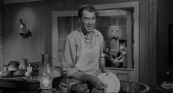 Movie still from “The Man Who Shot Liberty Valance” (1962), directed by John Ford – A man in an apron is holding a plate; Medium shot, Over the shoulder angle