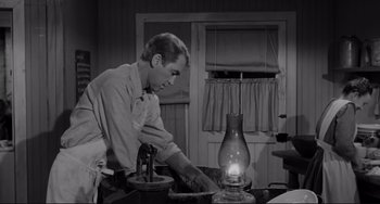 Movie still from “The Man Who Shot Liberty Valance” (1962), directed by John Ford – A man in a kitchen lighting a candle; Medium shot, Low angle