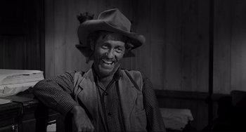 Movie still from “The Man Who Shot Liberty Valance” (1962), directed by John Ford – A black and white photo of a man wearing a cowboy hat; Medium shot, Over the shoulder angle