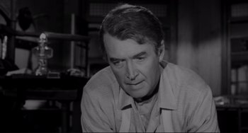 Movie still from “The Man Who Shot Liberty Valance” (1962), directed by John Ford – A black - and - white photo of a man looking down; Close Up shot, Over the shoulder angle