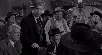 Movie still from “The Man Who Shot Liberty Valance” (1962), directed by John Ford – A black and white photo of a group of men wearing hats; Medium shot, Over the shoulder angle