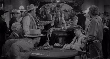 Movie still from “The Man Who Shot Liberty Valance” (1962), directed by John Ford – A black and white photo of men sitting at a table playing cards; Wide shot, High angle