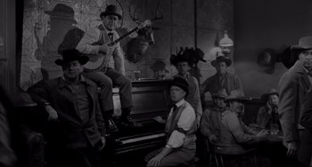 Movie still from “The Man Who Shot Liberty Valance” (1962), directed by John Ford – A black and white photo of a group of men in hats; Wide shot, High angle