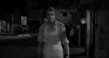 Movie still from “The Man Who Shot Liberty Valance” (1962), directed by John Ford – A man in an apron standing in front of an old barn; Medium shot, Over the shoulder angle