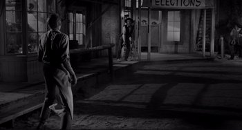 Movie still from “The Man Who Shot Liberty Valance” (1962), directed by John Ford – A man standing next to a woman in a room; Wide shot, Low angle