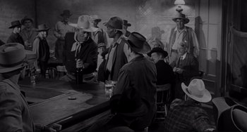 Movie still from “The Man Who Shot Liberty Valance” (1962), directed by John Ford – A black and white photo of a group of men drinking; Wide shot, Over the shoulder angle