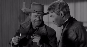 Movie still from “The Man Who Shot Liberty Valance” (1962), directed by John Ford – A man in a cowboy hat talking to another man in a suit; Medium shot, Over the shoulder angle