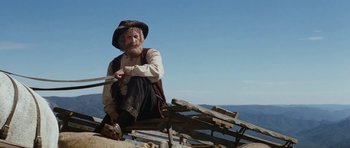 Movie still from “The Man from Snowy River” (1982), directed by George Miller – An old man sitting on top of a wooden structure; Medium shot, Low angle