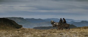 Movie still from “The Man from Snowy River” (1982), directed by George Miller – A man riding on the back of a horse drawn carriage on top of a hill; Extreme Wide shot, Low angle