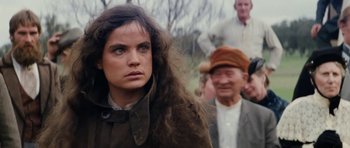 Movie still from “The Man from Snowy River” (1982), directed by George Miller – A woman with long brown hair standing in front of an older man; Close Up shot, Over the shoulder angle