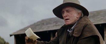 Movie still from “The Man from Snowy River” (1982), directed by George Miller – An old man in a hat holding a piece of paper in his hand; Close Up shot, Low angle