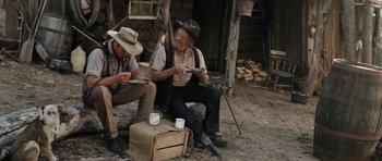 Movie still from “The Man from Snowy River” (1982), directed by George Miller – A couple of men sitting next to each other on a dirt ground; Wide shot, Low angle