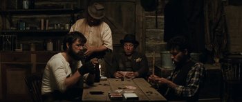 Movie still from “The Man from Snowy River” (1982), directed by George Miller – A group of men sitting at a table playing cards; Medium shot, Over the shoulder angle