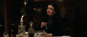 Movie still from “The Man from Snowy River” (1982), directed by George Miller – A woman sitting at a table holding a glass of wine; Medium shot, Over the shoulder angle