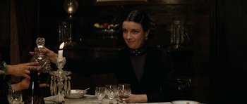 Movie still from “The Man from Snowy River” (1982), directed by George Miller – A woman sitting at a table with wine glasses in front of her; Medium shot, Over the shoulder angle