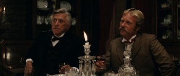 Movie still from “The Man from Snowy River” (1982), directed by George Miller – Two men sitting at a table with a lit candle in the middle; Close Up shot, Over the shoulder angle