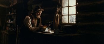 Movie still from “The Man from Snowy River” (1982), directed by George Miller – An old man sitting at a table in front of a window; Medium shot, Low angle