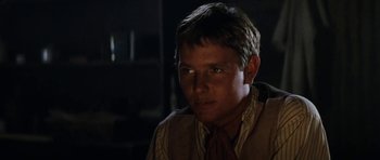Movie still from “The Man from Snowy River” (1982), directed by George Miller – A young man in a brown vest and a red neck tie; Close Up shot, Low angle