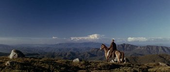 Movie still from “The Man from Snowy River” (1982), directed by George Miller – A man riding a horse on top of a hill; Extreme Wide shot, Low angle