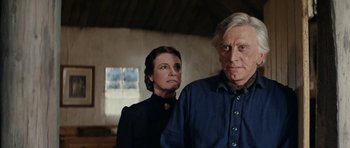 Movie still from “The Man from Snowy River” (1982), directed by George Miller – A man and a woman standing next to each other in a room; Close Up shot, Low angle