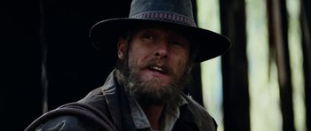 Movie still from “The Man from Snowy River” (1982), directed by George Miller – A man with a beard wearing a hat and jacket; Close Up shot, Low angle
