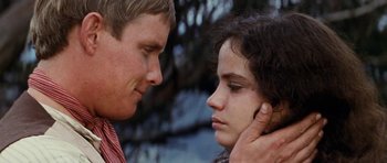 Movie still from “The Man from Snowy River” (1982), directed by George Miller – A man and a woman face to face in front of trees; Close Up shot, Over the shoulder angle