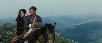Movie still from “The Man from Snowy River” (1982), directed by George Miller – A man riding on the back of a brown horse; Medium shot, Low angle