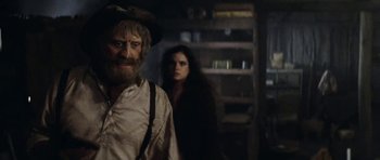 Movie still from “The Man from Snowy River” (1982), directed by George Miller – A man and a woman standing in front of a bookshelf; Medium shot, Over the shoulder angle