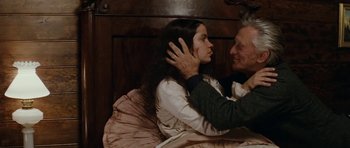Movie still from “The Man from Snowy River” (1982), directed by George Miller – A man and a woman in a bed with one of them touching the other's face; Medium shot, High angle