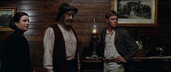 Movie still from “The Man from Snowy River” (1982), directed by George Miller – Two men standing next to each other in front of a lamp; Medium shot, Low angle