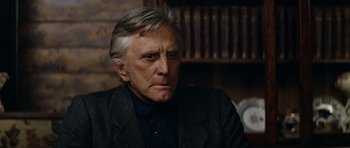 Movie still from “The Man from Snowy River” (1982), directed by George Miller – An older man in a suit sitting in front of a book shelf; Close Up shot, Low angle