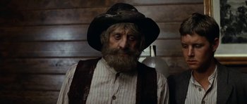 Movie still from “The Man from Snowy River” (1982), directed by George Miller – An old man with a beard wearing a cowboy hat; Close Up shot, Low angle