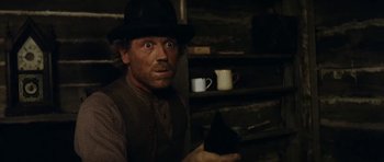 Movie still from “The Man from Snowy River” (1982), directed by George Miller – A man in a black hat holding a black object; Close Up shot, Low angle