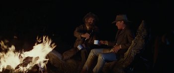 Movie still from “The Man from Snowy River” (1982), directed by George Miller – Two men sitting next to each other at night drinking coffee; Medium shot, Low angle