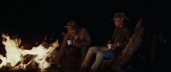 Movie still from “The Man from Snowy River” (1982), directed by George Miller – A group of men sitting next to each other on the ground; Wide shot, Low angle