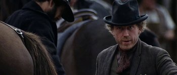 Movie still from “The Man from Snowy River” (1982), directed by George Miller – A man wearing a hat and a tie standing next to another man in a hat; Close Up shot, Low angle