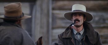 Movie still from “The Man from Snowy River” (1982), directed by George Miller – A man with a beard and a hat smoking a pipe; Close Up shot, Low angle