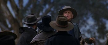 Movie still from “The Man from Snowy River” (1982), directed by George Miller – A group of people wearing hats and talking to each other; Close Up shot, Over the shoulder angle