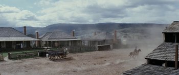 Movie still from “The Man from Snowy River” (1982), directed by George Miller – An old fashioned wagon in the middle of a dirt field; Extreme Wide shot, Low angle