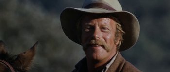 Movie still from “The Man from Snowy River” (1982), directed by George Miller – An older man wearing a cowboy hat and smiling for the camera; Close Up shot, Low angle